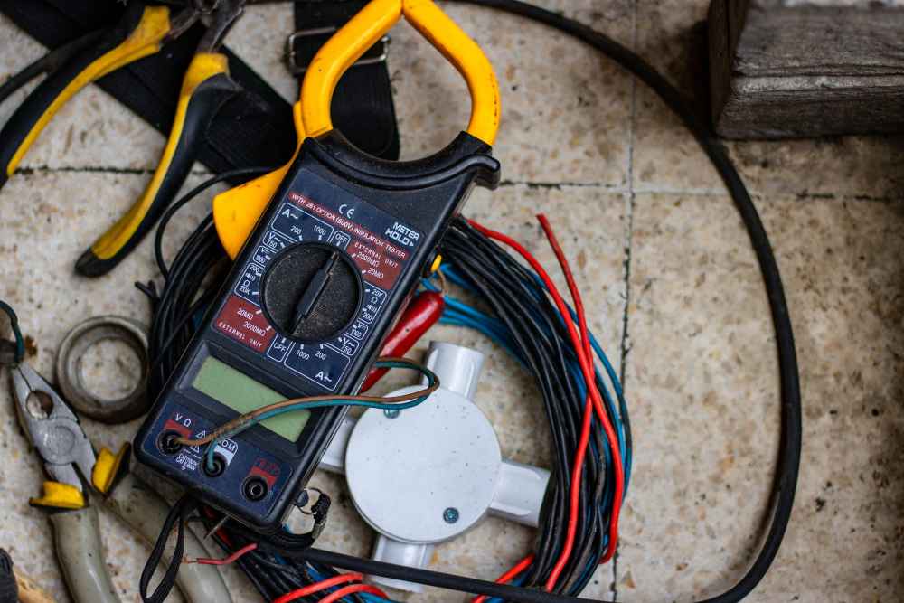 Electrical multimeter with wires and tools on a tiled floor.