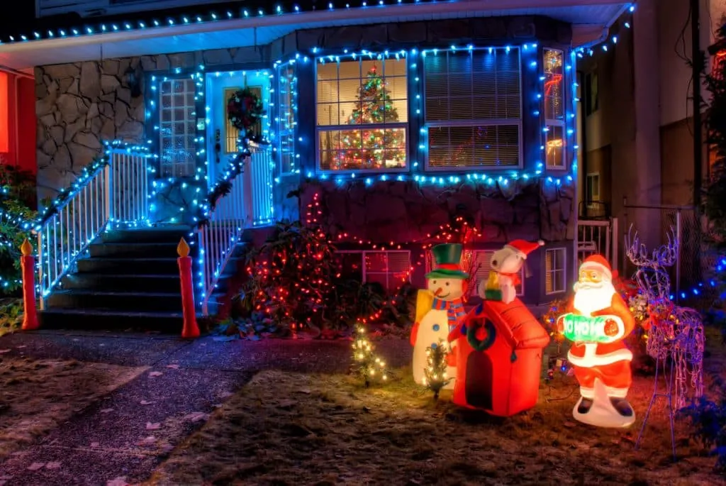 House decorated with bright Christmas lights and inflatable holiday figures.