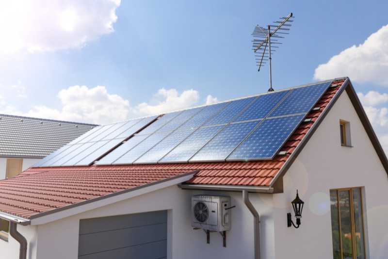 Rooftop solar panel system installed on a modern house under sunny sky.