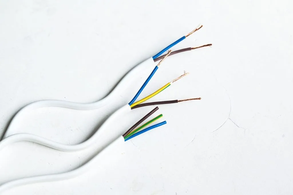 Three white electrical cables with exposed copper wire ends.