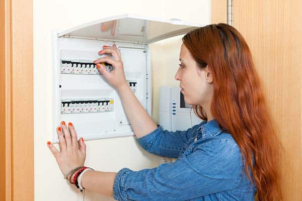 Woman checking a residential electrical breaker panel.