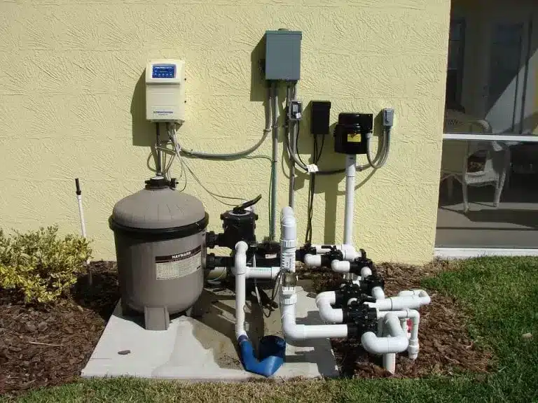 Outdoor pool pump and filtration system mounted on a concrete slab.